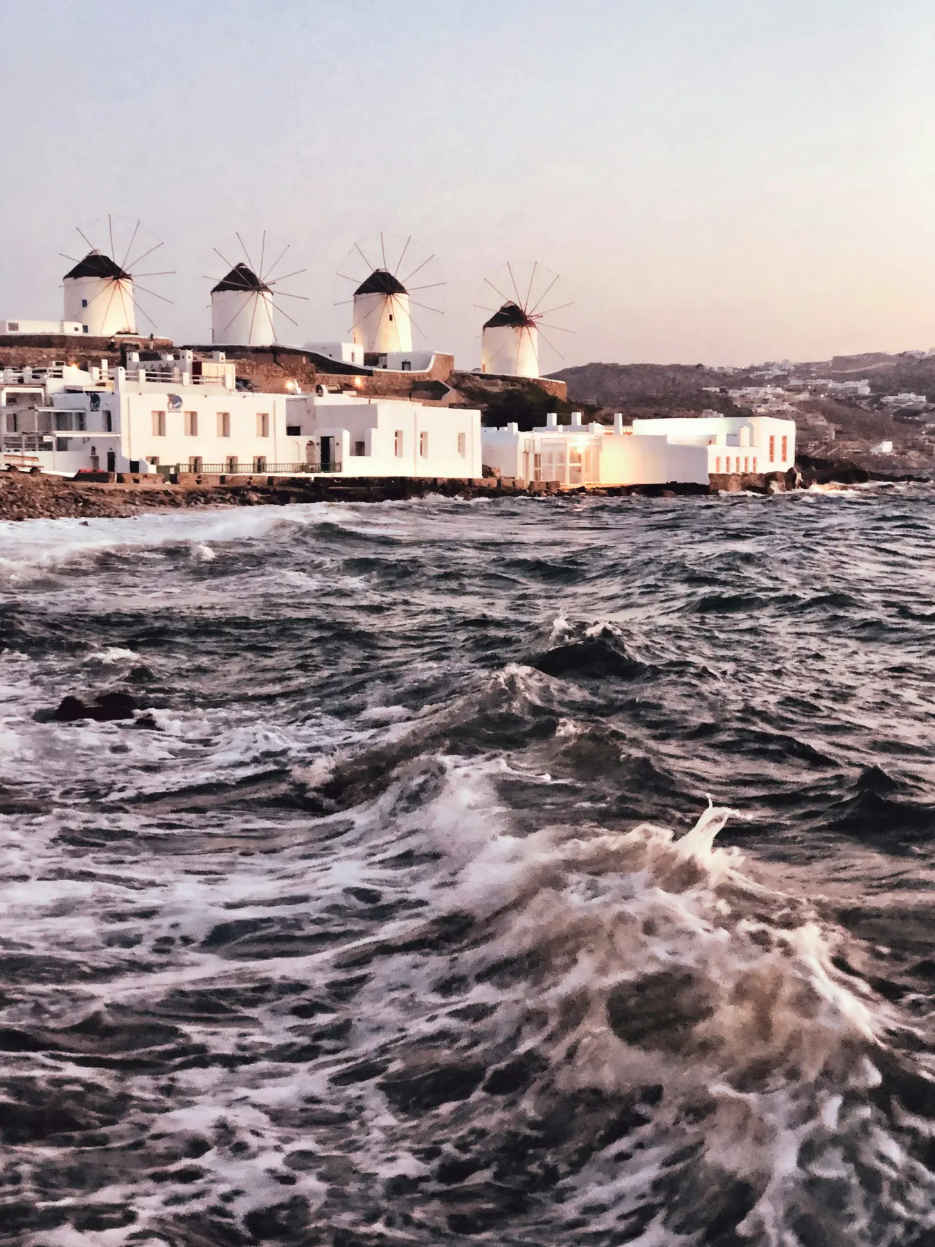 Mykonos windmills and white waterfront buildings at sunset